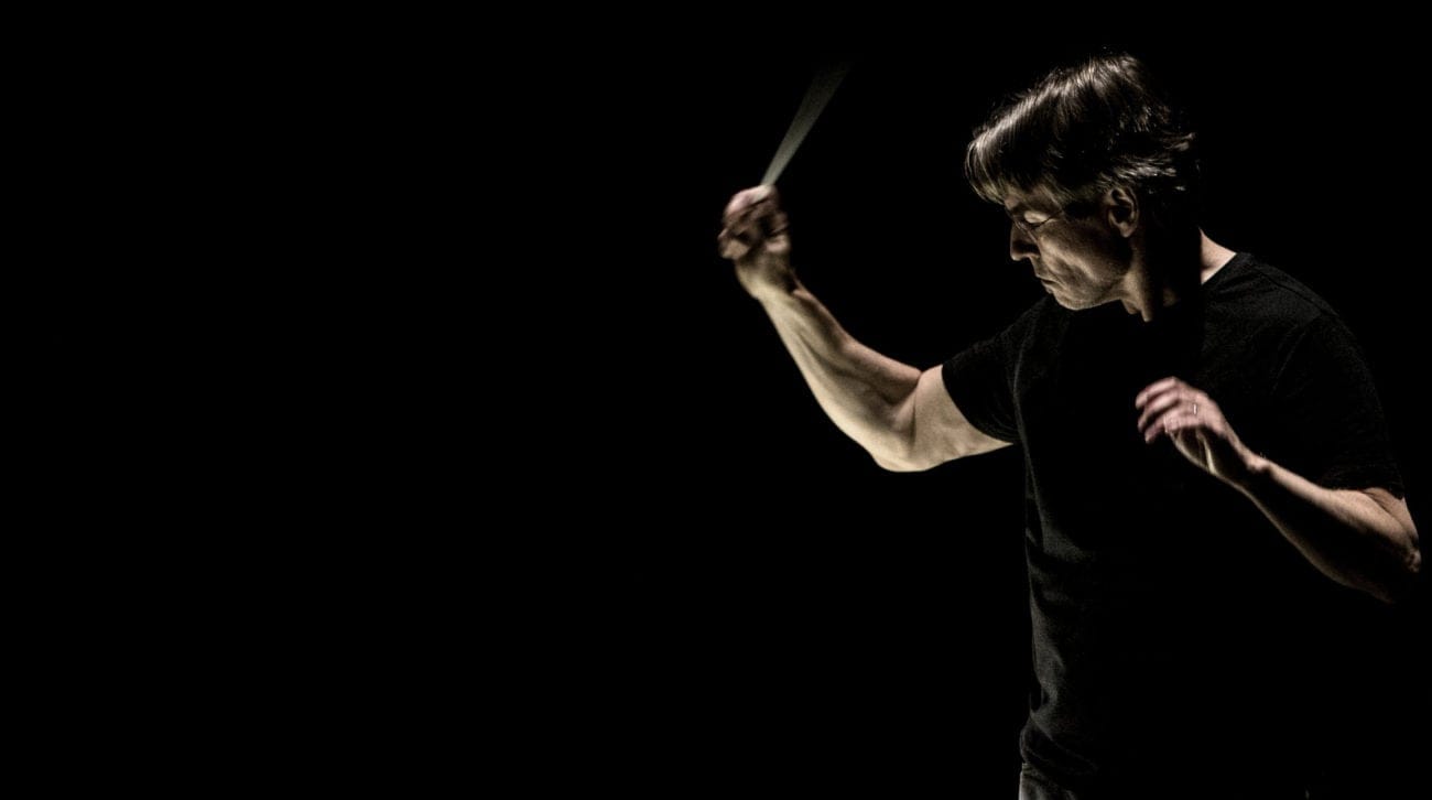 Esa-Pekka Salonen conducting in moody, darkly lit photo