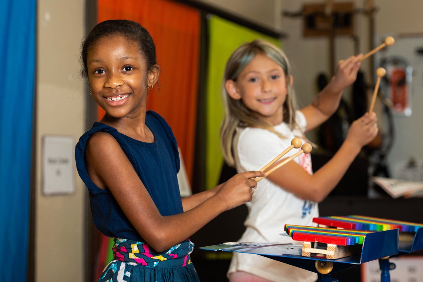 Two girls at school posing with xylophone mallets