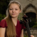 Amelia Zitoun holds cello in courtyard