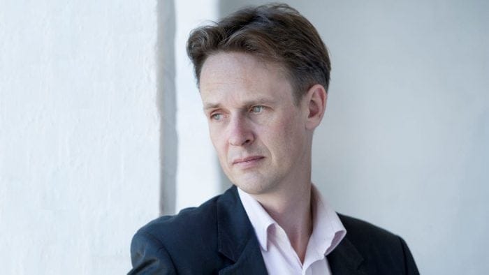 Portrait of Ian Bostridge looking over right shoulder, very white back ground.