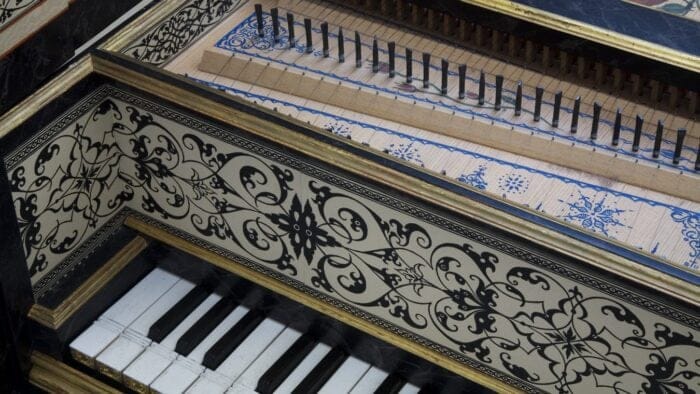 detail of an ornate 17th-century harpsichord, featuring an octave of keys, and part of the soundbopard