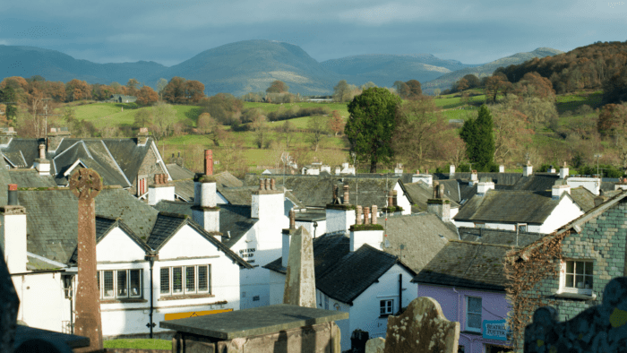 A view of the roof tops of the village of Hawkshead across to the Cumbrian hills in the distance including red screes and ill bell