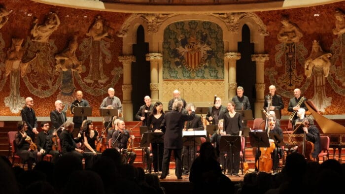 The instrumental ensemble Le Concert des Nations being conducted by Jordi Savall in concert in the ornate Palau de la Música Catalana.