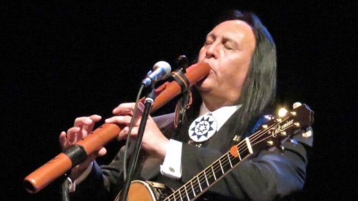 indigenous man plays traditional flute