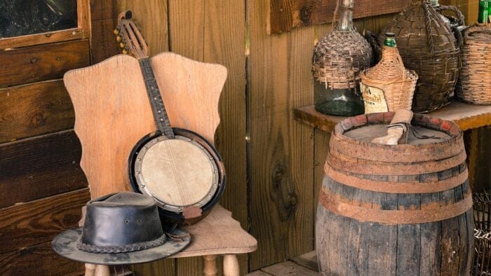 a hat and banjo on a chair next to a barrel
