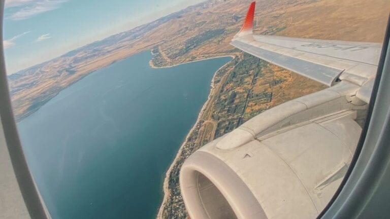 Looking out a window of an airplane onto a town by the lake