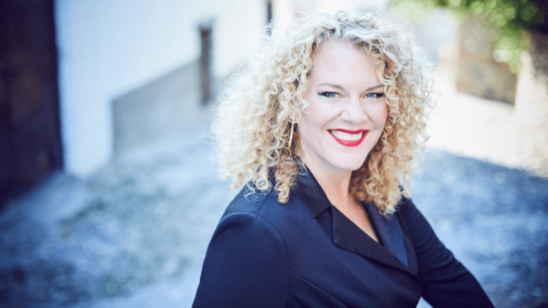 Michelle DeYoung portrait in navy blue pantsuit with an urban-industrial background.