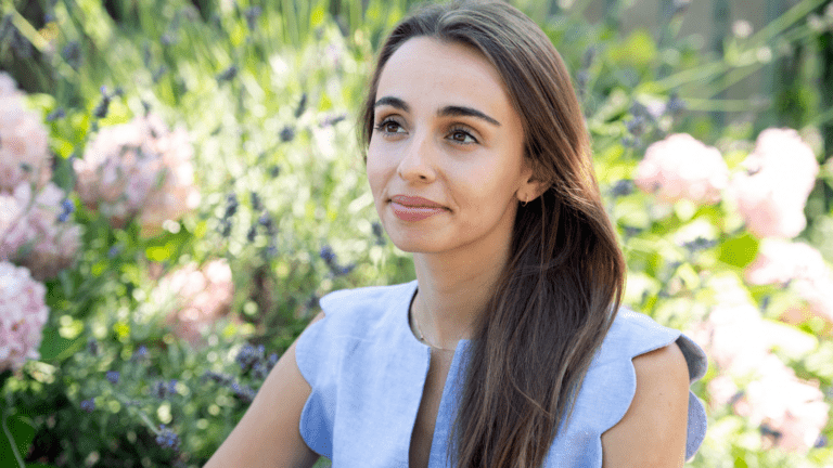 Portrait of Lea Desandre in sleeveless light blue linen blouse, garden background out of focust