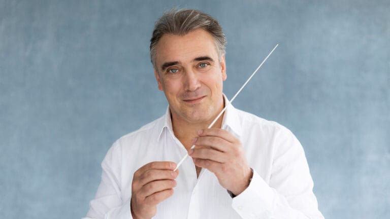 Jaime Martín holds his conductor's baton in front of a blue background