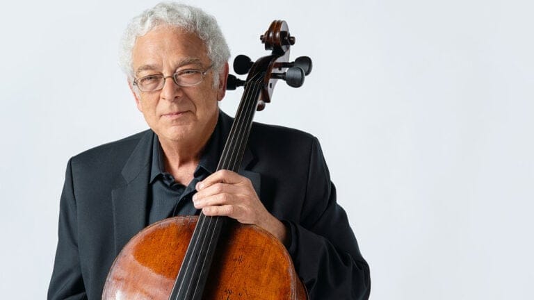 Studio portrait of cellist David Sanders, with instrument, in front of a white background