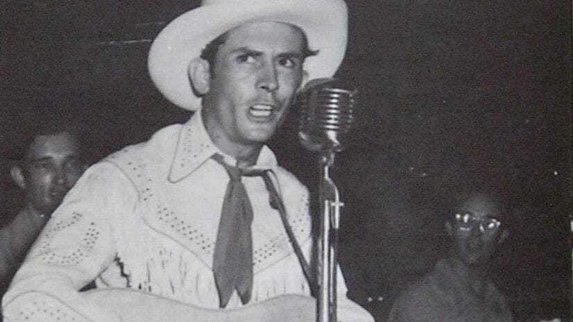 man in cowboy hat sings into vintage microphone