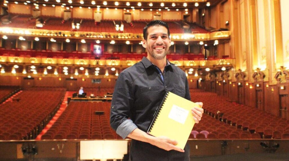 Composer Jimmy López proudly displays the completed piano-vocal score of his first opera, “Bel Canto,” on the stage of the Ardis Krainik Theatre in the Civic Opera House, home of Lyric Opera of Chicago.