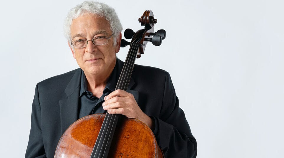 Studio portrait of cellist David Sanders, with instrument, in front of a white background