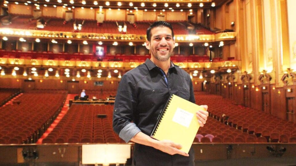 Composer Jimmy López proudly displays the completed piano-vocal score of his first opera, “Bel Canto,” on the stage of the Ardis Krainik Theatre in the Civic Opera House, home of Lyric Opera of Chicago.