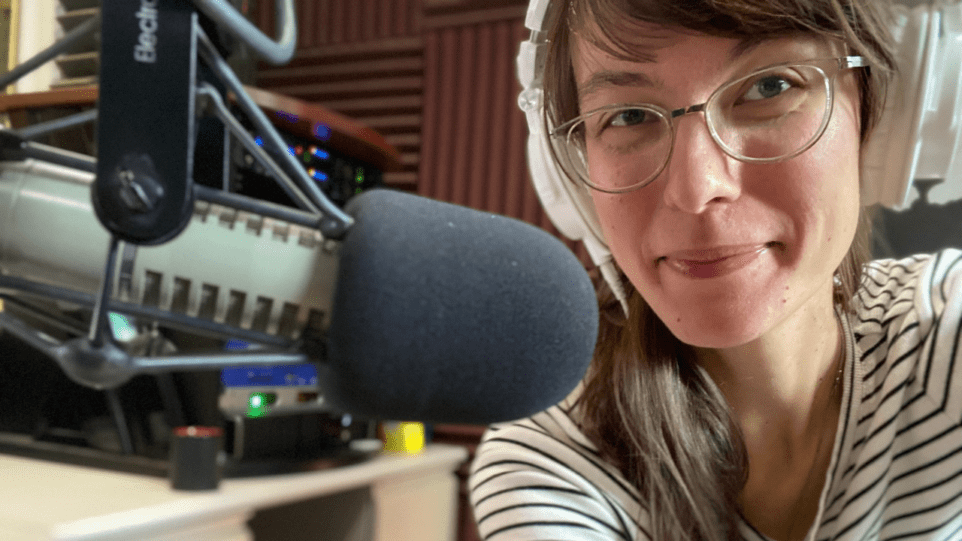 Selfie of Adela Skowronski in radio studio in front of announcer microphone