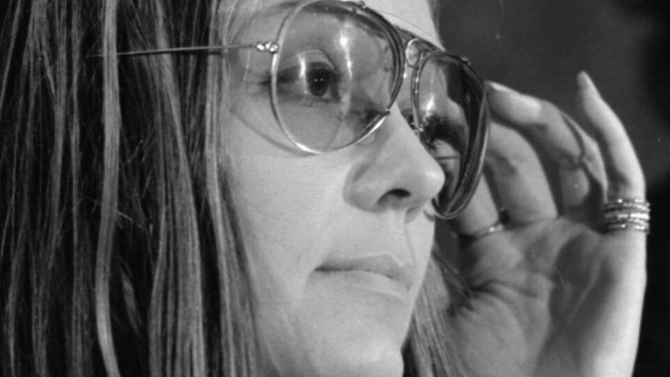 tight closeup of Gloria Steinem adjusting her glasses