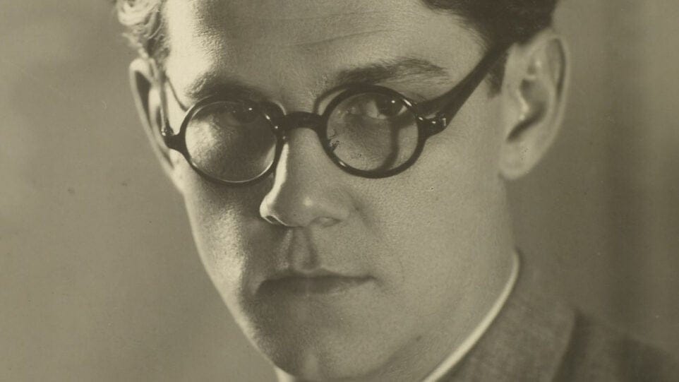 A close up black and white photo of Radamés Gnattali, in glasses, gazing away from the camera