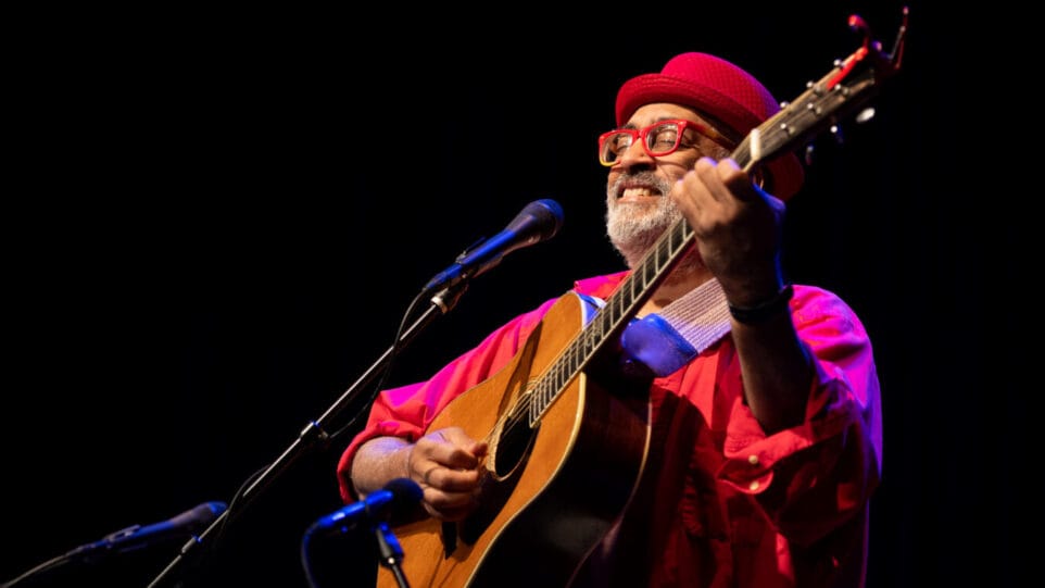 smiling man in red hat playing guitar