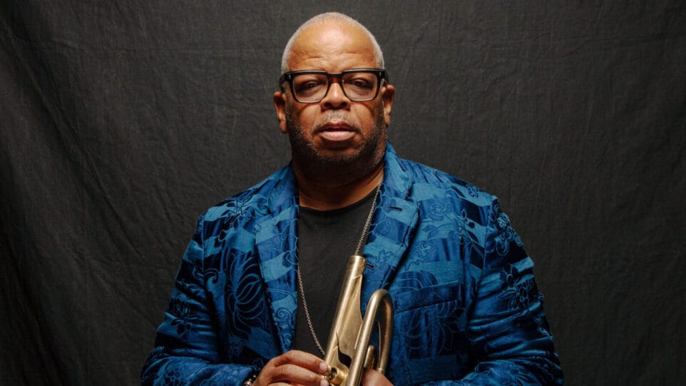 Terence Blanchard, in a patterned blue suit coat, holds a trumpet