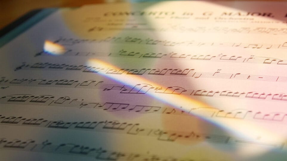 sheet music of a concerto dappled by a refracted beam of light with the colors of the rainbow visible