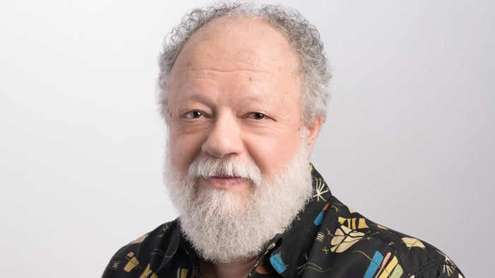 Man with white hair and beard and colorful shirt