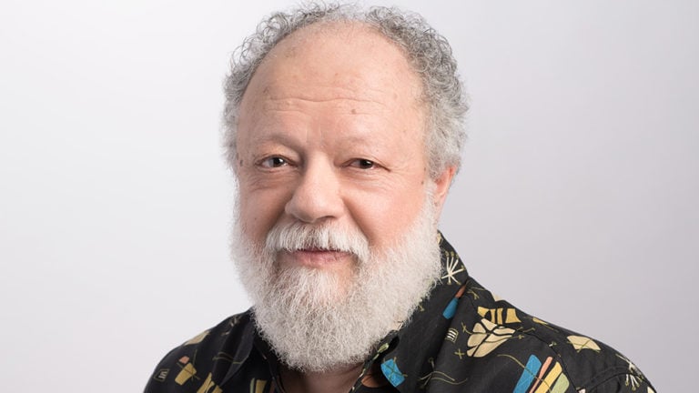 Man with white hair and beard and colorful shirt