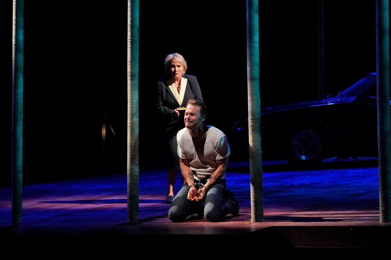 Ryan McKinny, in agony and on his knees, onstage with Patricia Racette, sorrowfully in Lyric Opera of Chicago's 'Dead Man Walking'