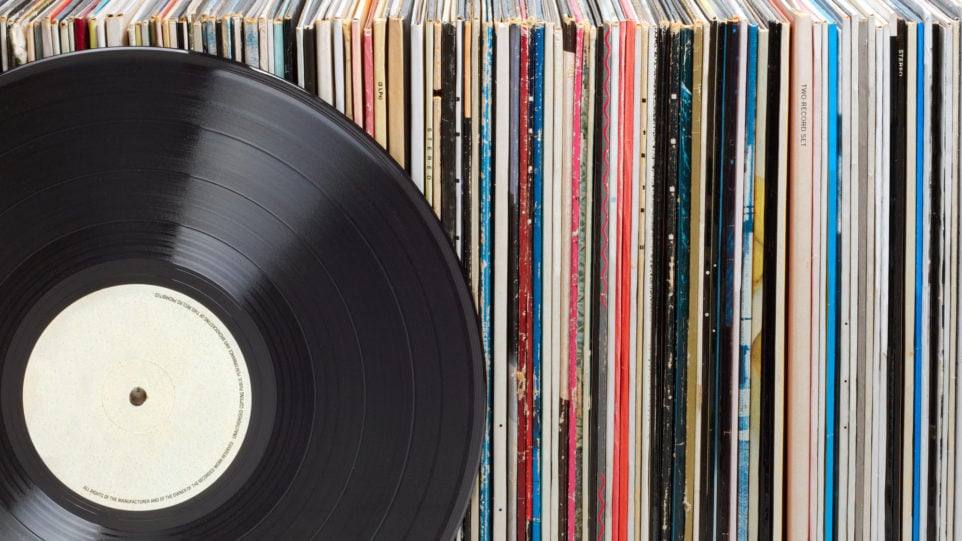 closeup of a vinyl record and a stack of record package spines
