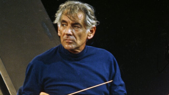 Leonard Bernstein, in a blue turtleneck, leads rehearsal