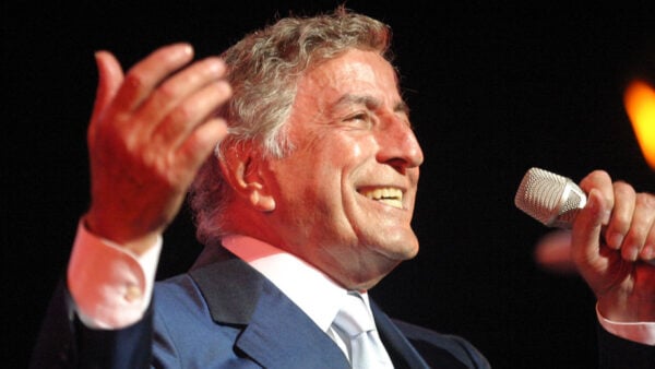 Tony Bennett holds a microphone and sings onstage