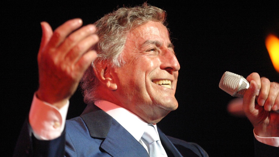 Tony Bennett holds a microphone and sings onstage