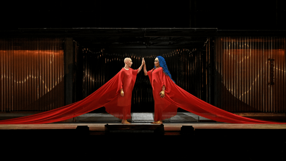 Akhnaten and Nefertiti identically dressed in red gowns, symmetrical image, touching hands.