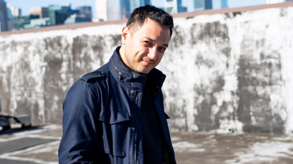 Portrait of Nicholas Phan in urban landscape wearing a black coat