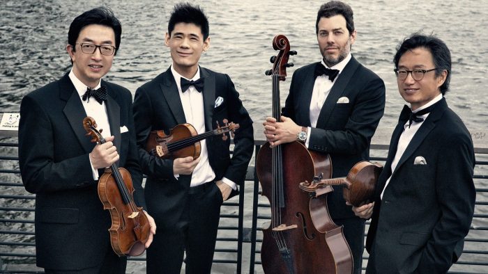 Four men in tuxedos holding string instruments
