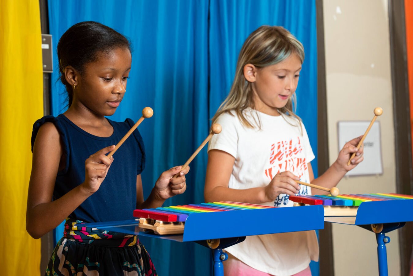 Two girls learning to play xylophones