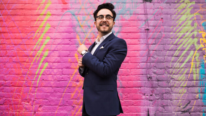 Julian Velasco in front of a bright, multicolored wall