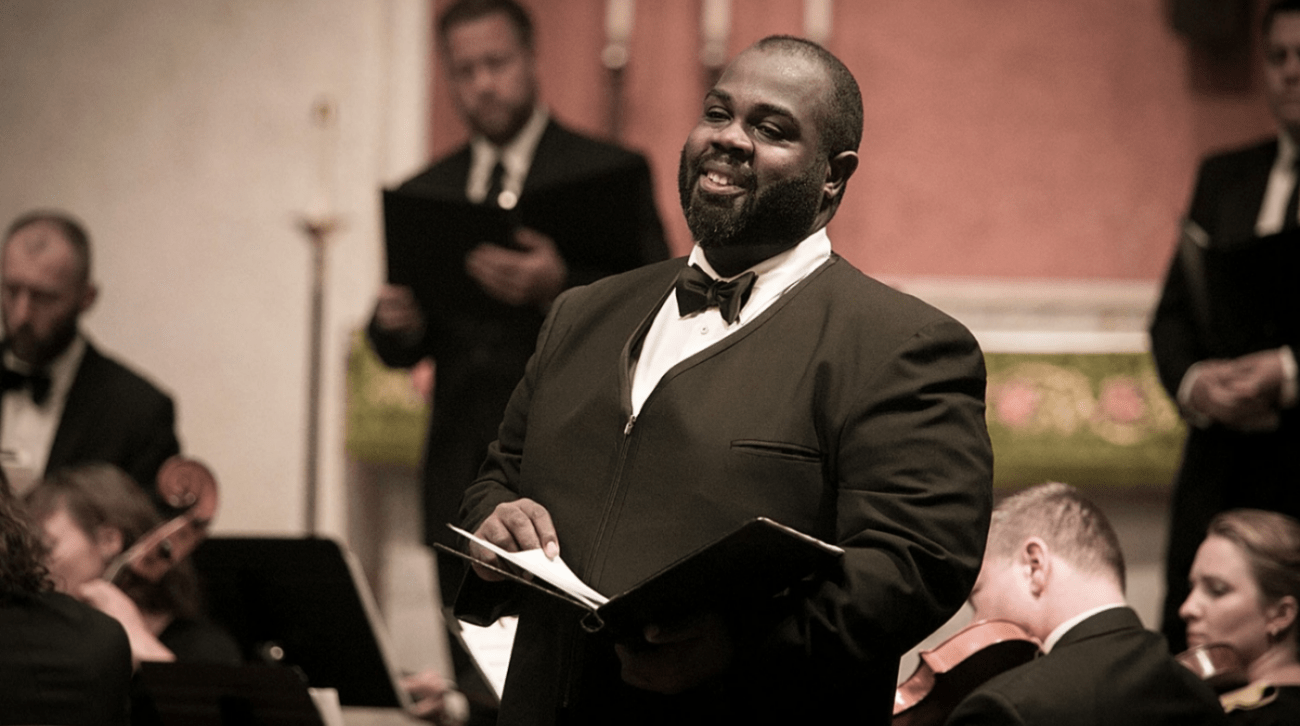 Reginald Mobley in performance waering tuxedo, holding music at waist