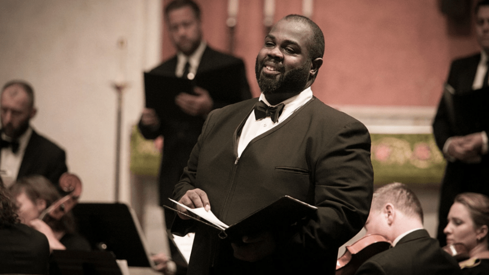 Reginald Mobley in performance waering tuxedo, holding music at waist