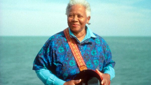 Gray haired woman stands with the ocean to her back