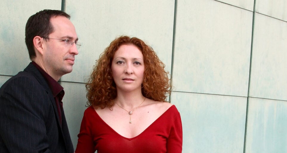 Cavatina Duo — Denis Azabagic in black and Eugenia Molliner in red — pose against a metal tiled wall