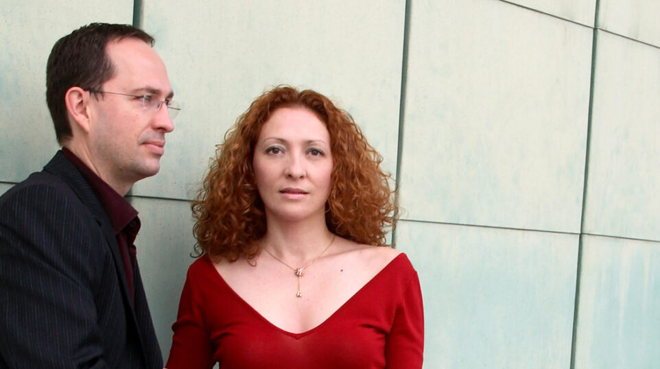 Cavatina Duo — Denis Azabagic in black and Eugenia Molliner in red — pose against a metal tiled wall