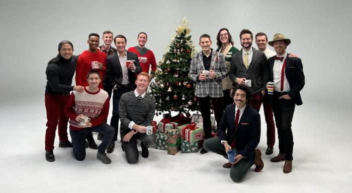 portrait of the all-male ensemble in festive holiday attire around a decorated Christmas Tree