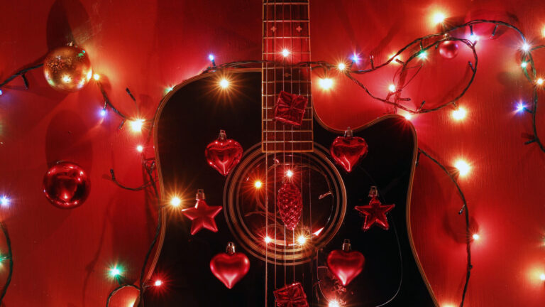 a guitar strung with holiday lights and ornaments