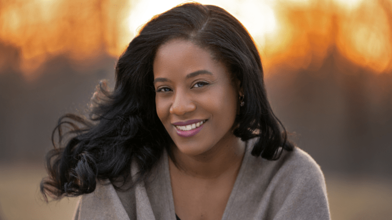 Portrait of Sonya Headlam in grey cahmere wrap against a warm abstract background that suggests sunset