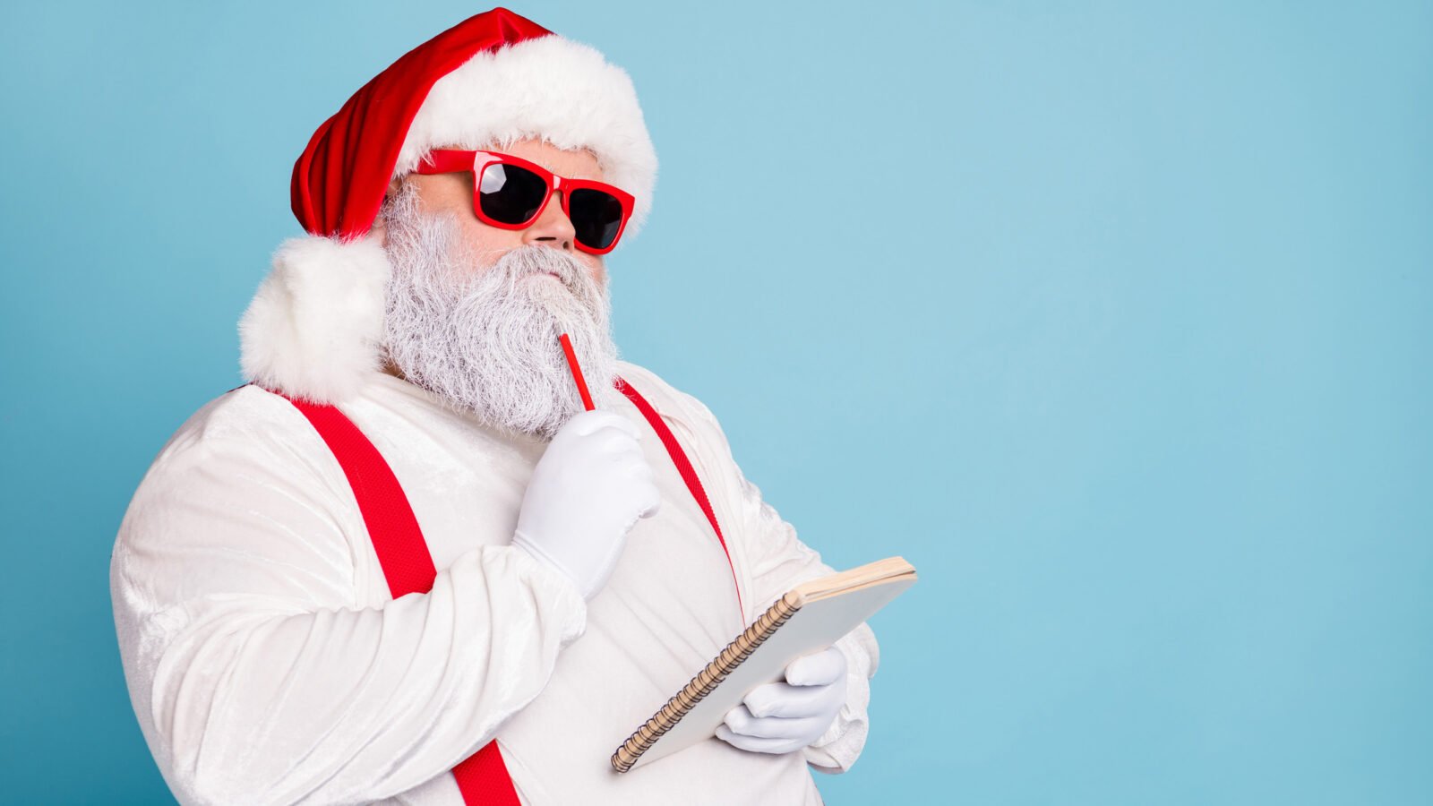A sunglasses-wearing Santa ponders his list