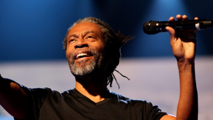 Bobby McFerrin smiles, holding microphone