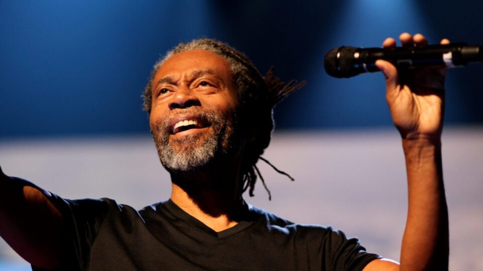 Bobby McFerrin smiles, holding microphone