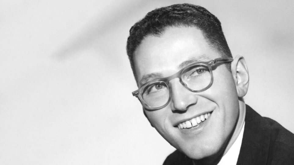 close up of Tom Lehrer smiling, wearing glasses