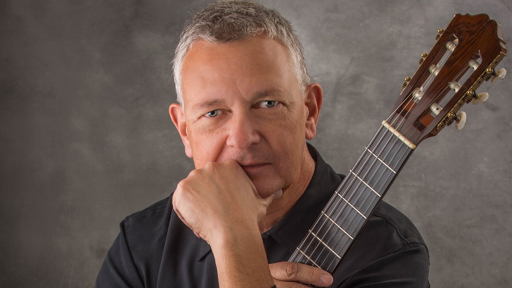 Christopher Laughlin stares pensively, holding a guitar