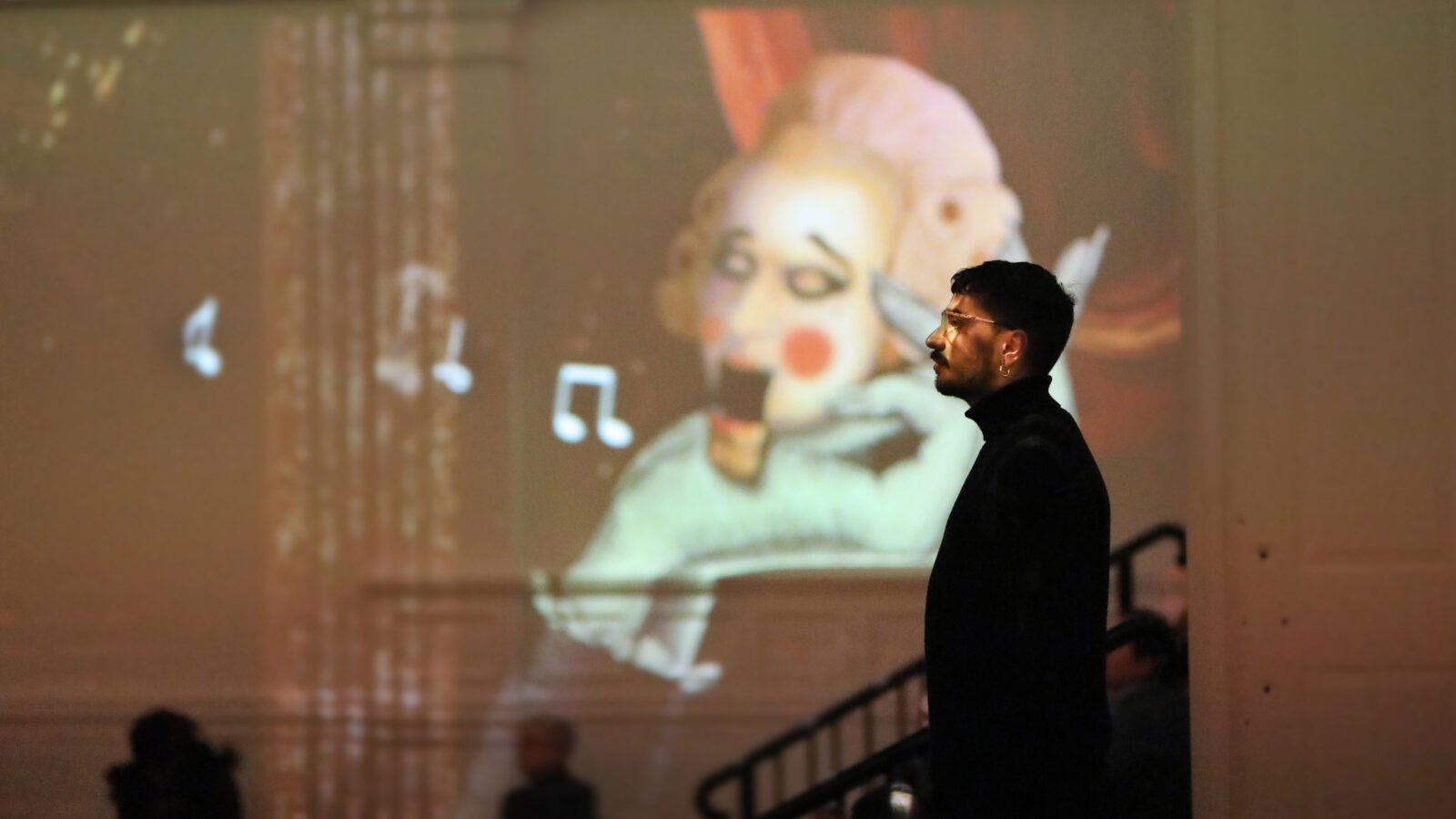 an audience member surveys the Immersive Mozart exhibition, with a frame visible in the background